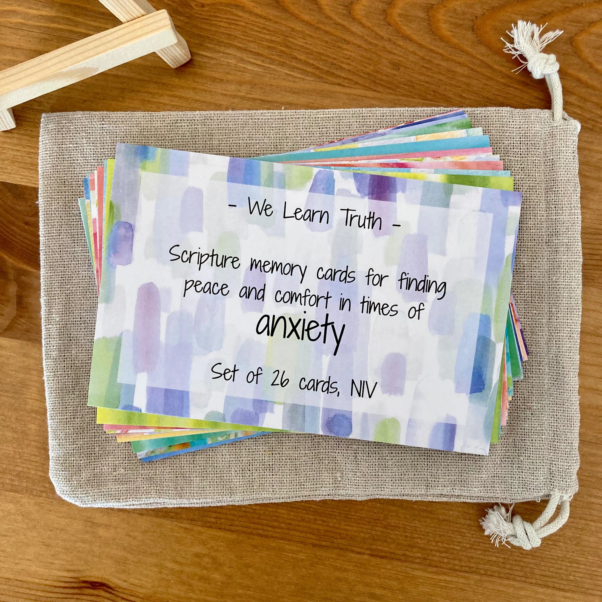 Set of Scripture memory cards for anxiety on a canvas storage bag on a wooden surface. Wooden easel (included) if off to the side.