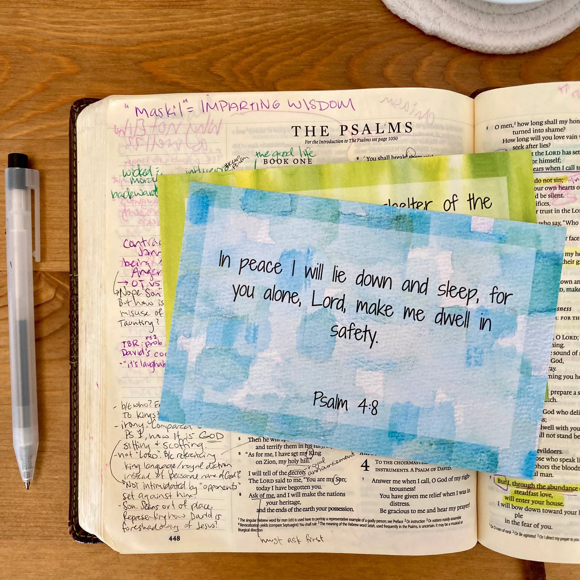 Scripture memory card on an open bible on a wooden surface. Card has a colorful geometric design with the verse of Psalm 4:8, a verse about anxiety.