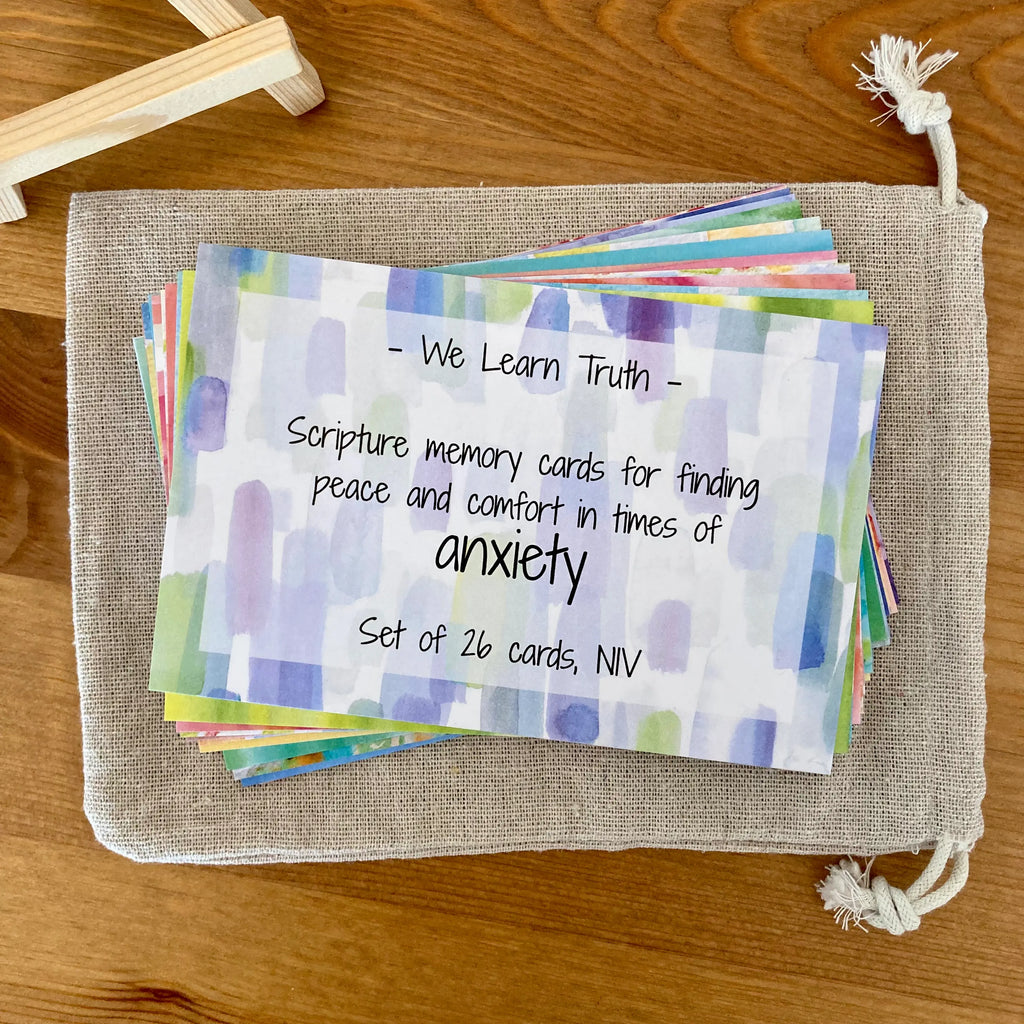 Set of Scripture memory cards for anxiety on a canvas storage bag on a wooden surface. Wooden easel (included) if off to the side.