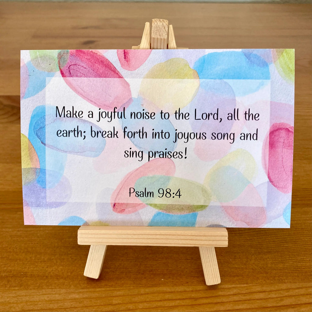 Colorful card with Psalm 98:4 text on a wooden easel.