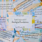 A set of 50 scripture memory cards with watercolor designs, featuring the text "We Learn Truth - Scripture memory cards of theological foundations, Set of 50 cards, ESV" prominently displayed, surrounded by other cards with various Bible verses, arranged on a flat surface